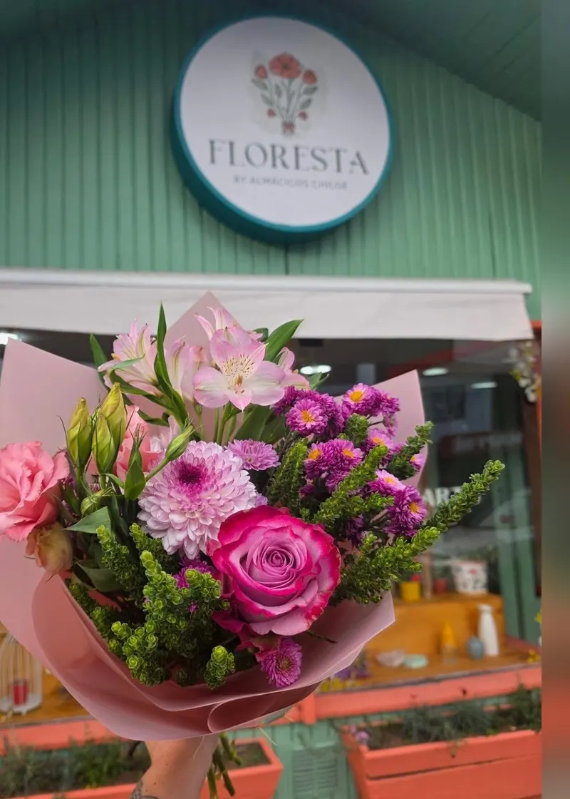 Ramo de rosas, lisianthus y alstroemerias rosadas frente al letrero de Floresta