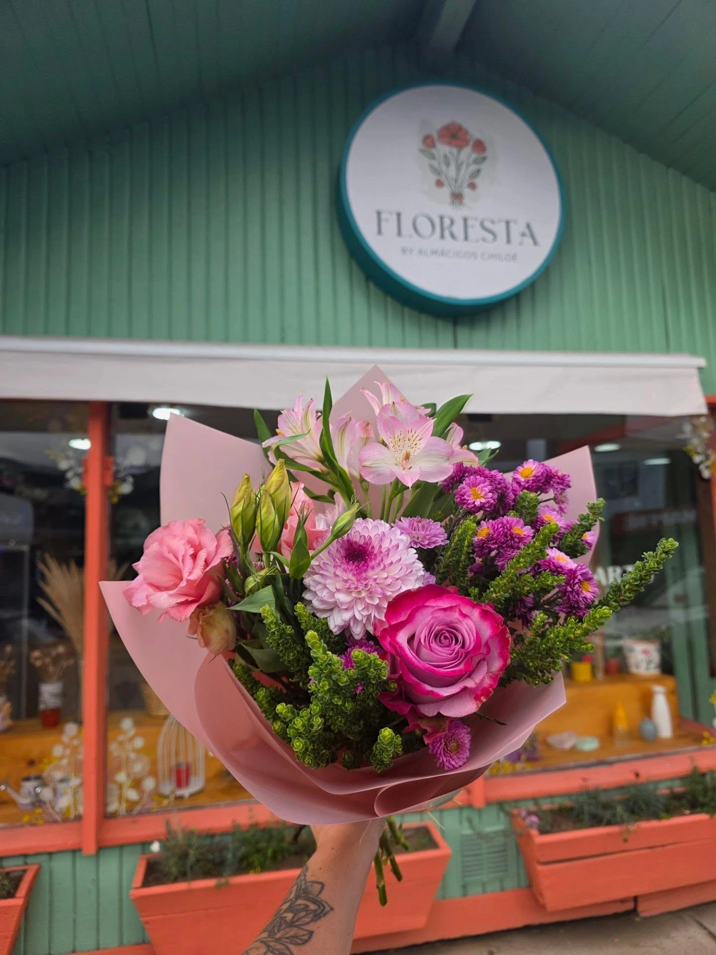 Ramo de rosas, lisianthus y alstroemerias rosadas frente a la florería