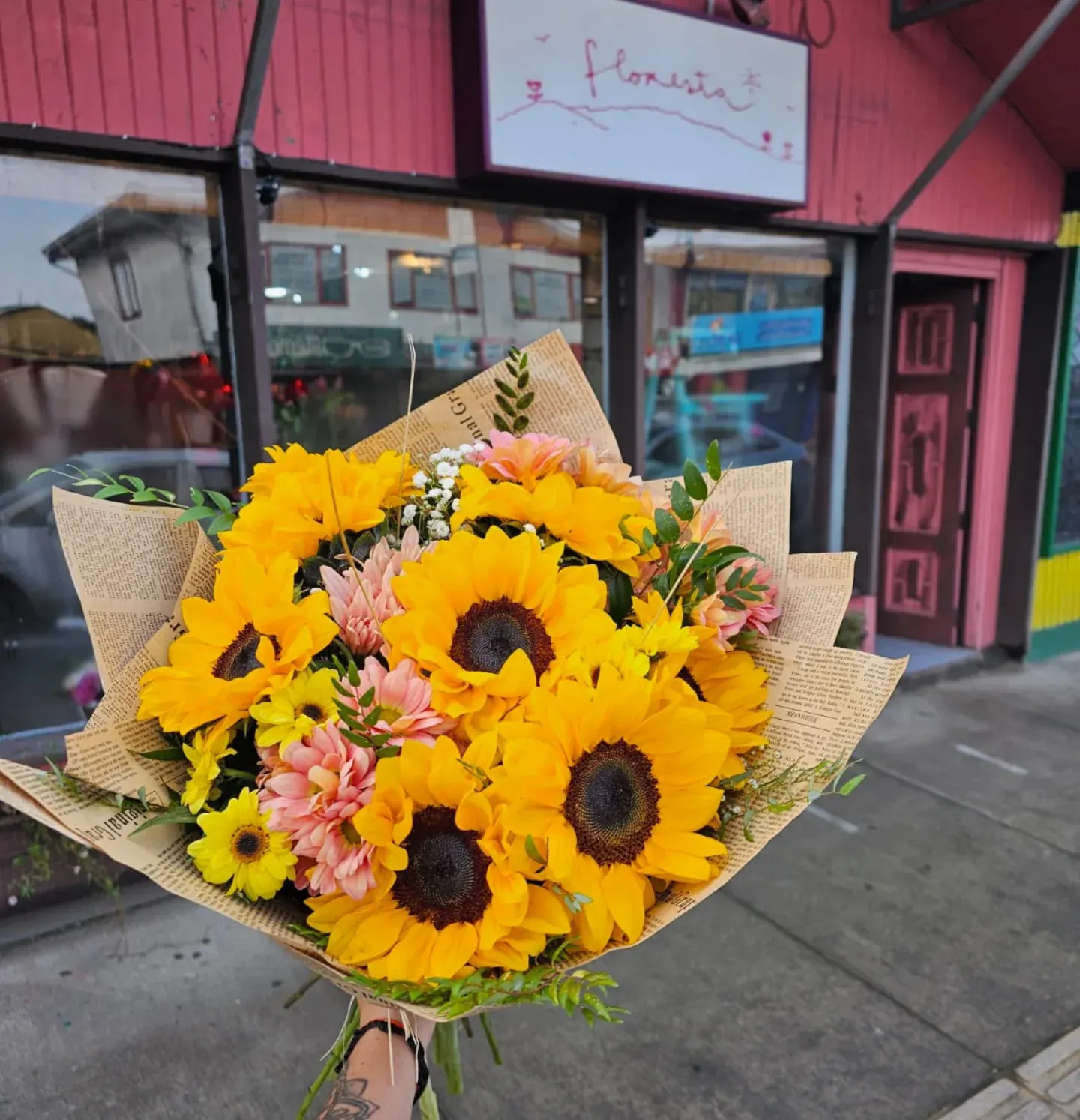 Ramo de girasoles envuelto en papel kraft frente a la florería