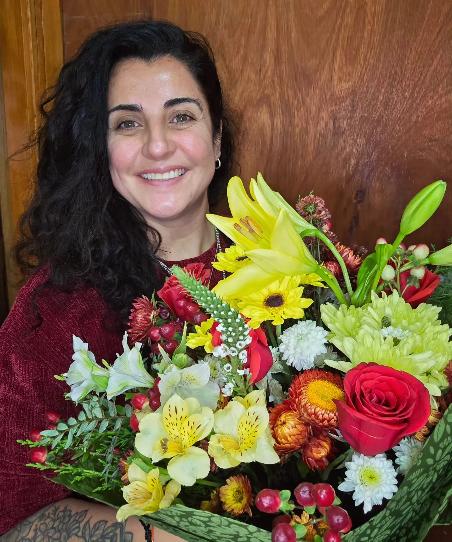 Natalia Torres Manzo sonriendo con un ramo de lirios, rosas y flores amarillas