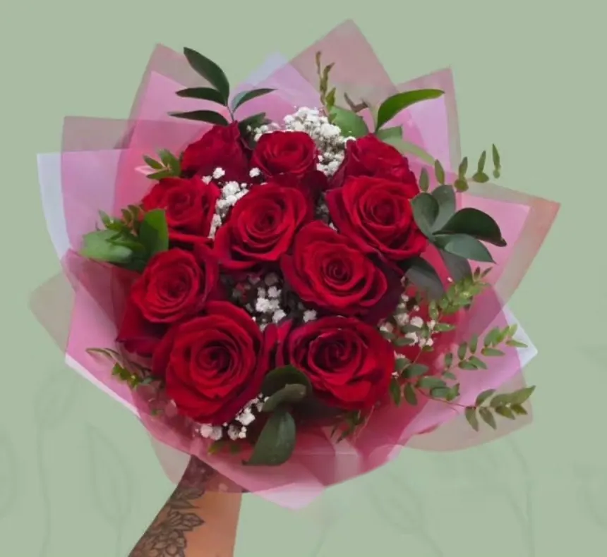 Ramo de rosas rojas en papel rosado sostenido en alto